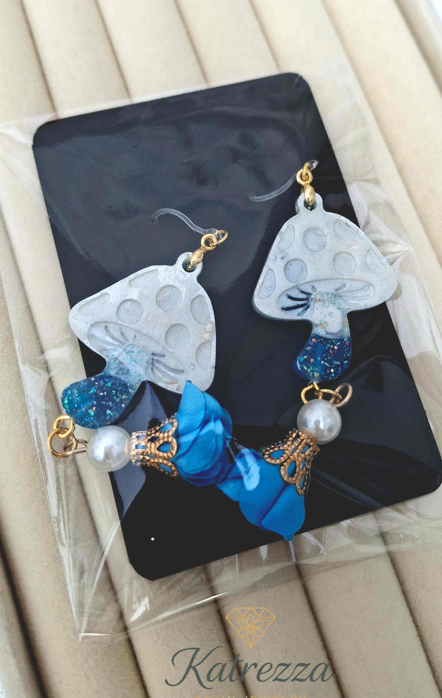 "Double-sided resin mushroom earrings, one glossy blue and one glittery white with blue stem, accented with pearls and flower charms – Katrezza Jewelry"