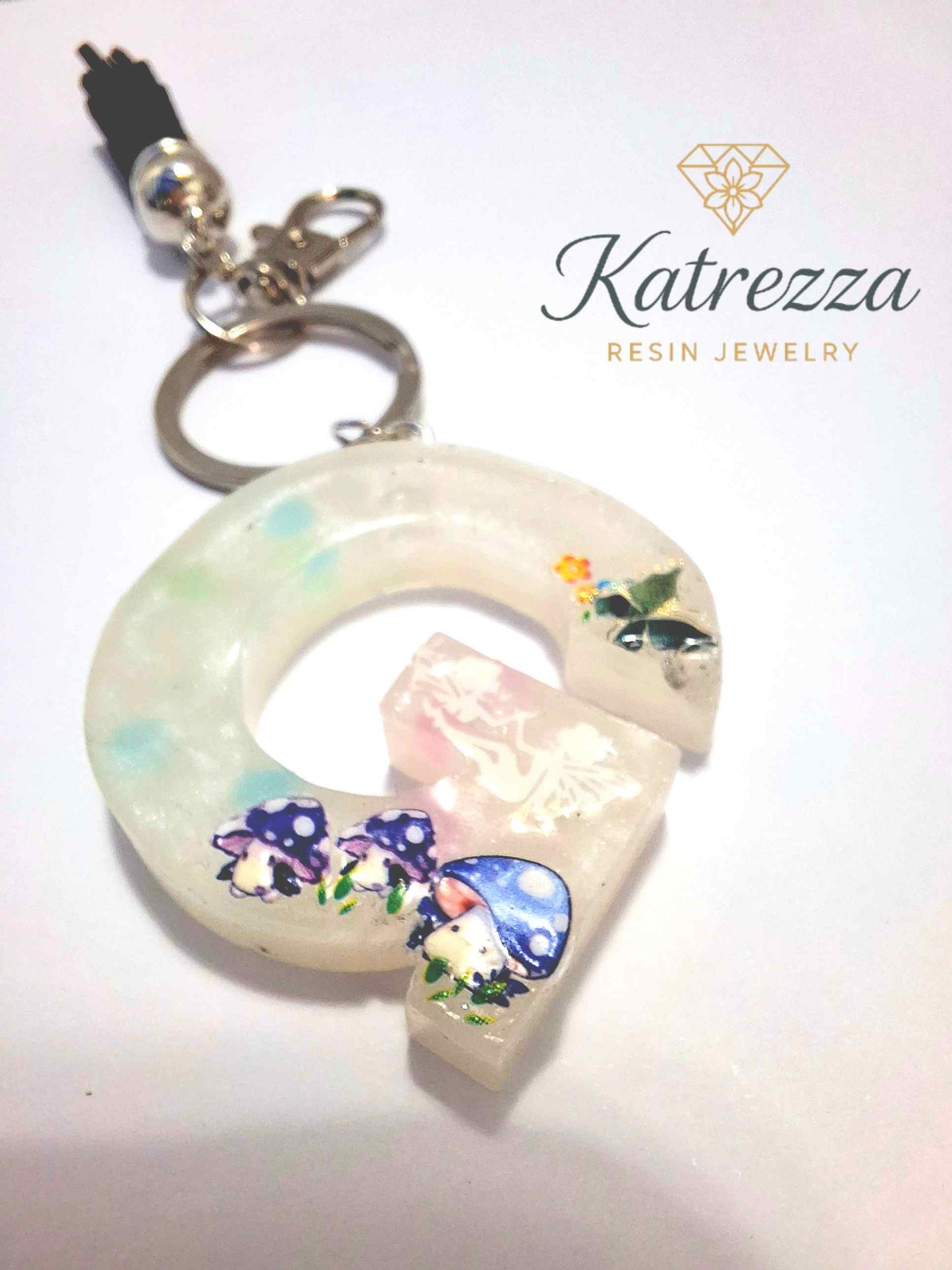 Handmade resin G keychain with fairy silhouette, mushrooms, and butterfly decorati