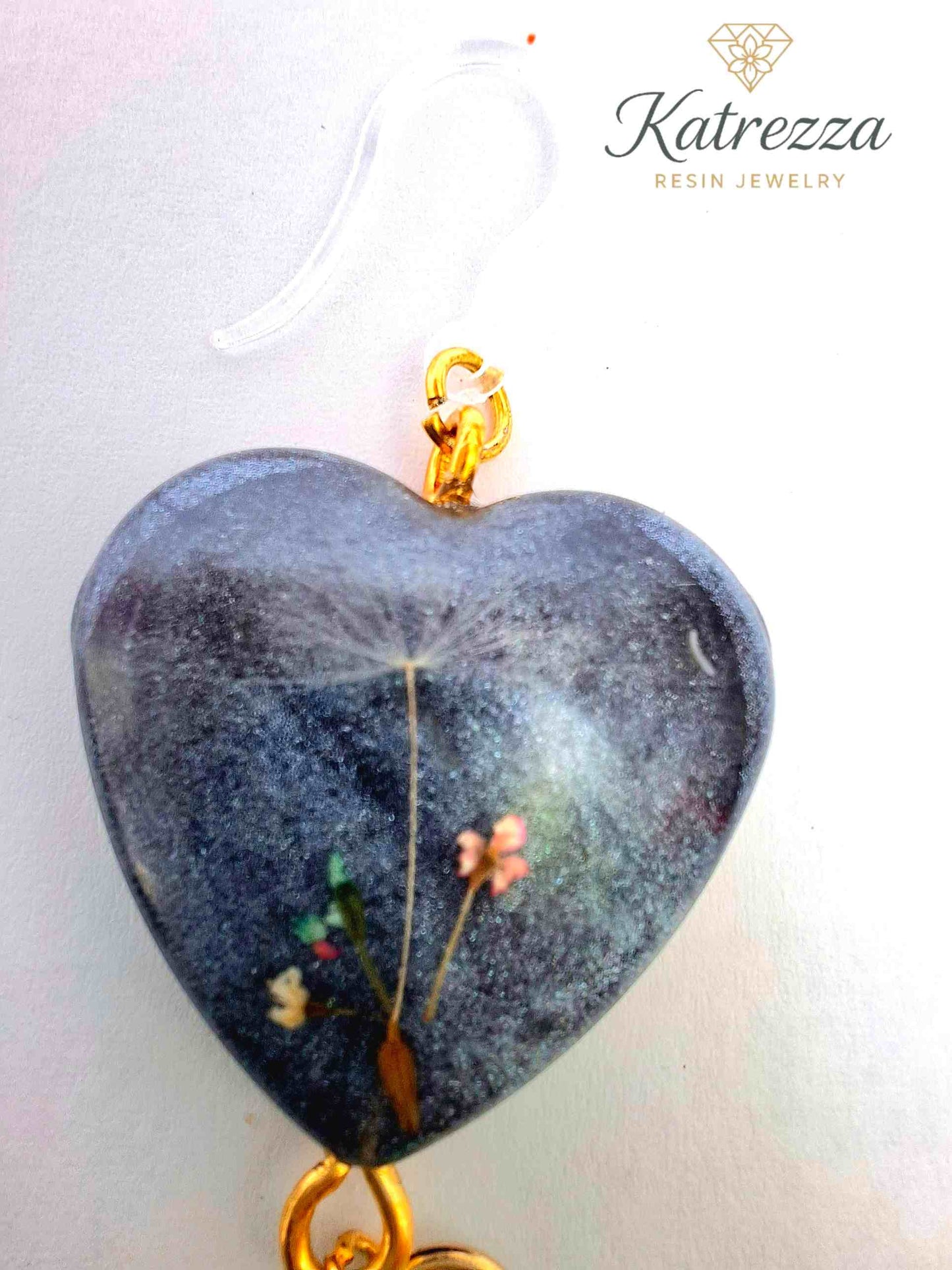 “Handmade heart resin earrings with gold accents, silicone hooks, and mint green tassels.”