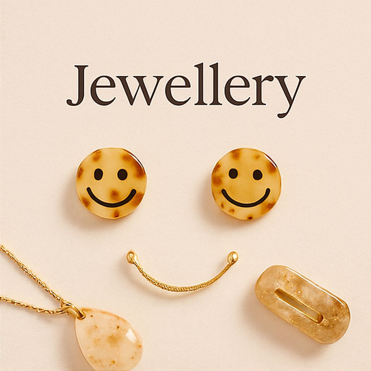 Smiley resin stud earrings and gold necklace arranged playfully on a cream background – Katrezza Jewellery Collection.
