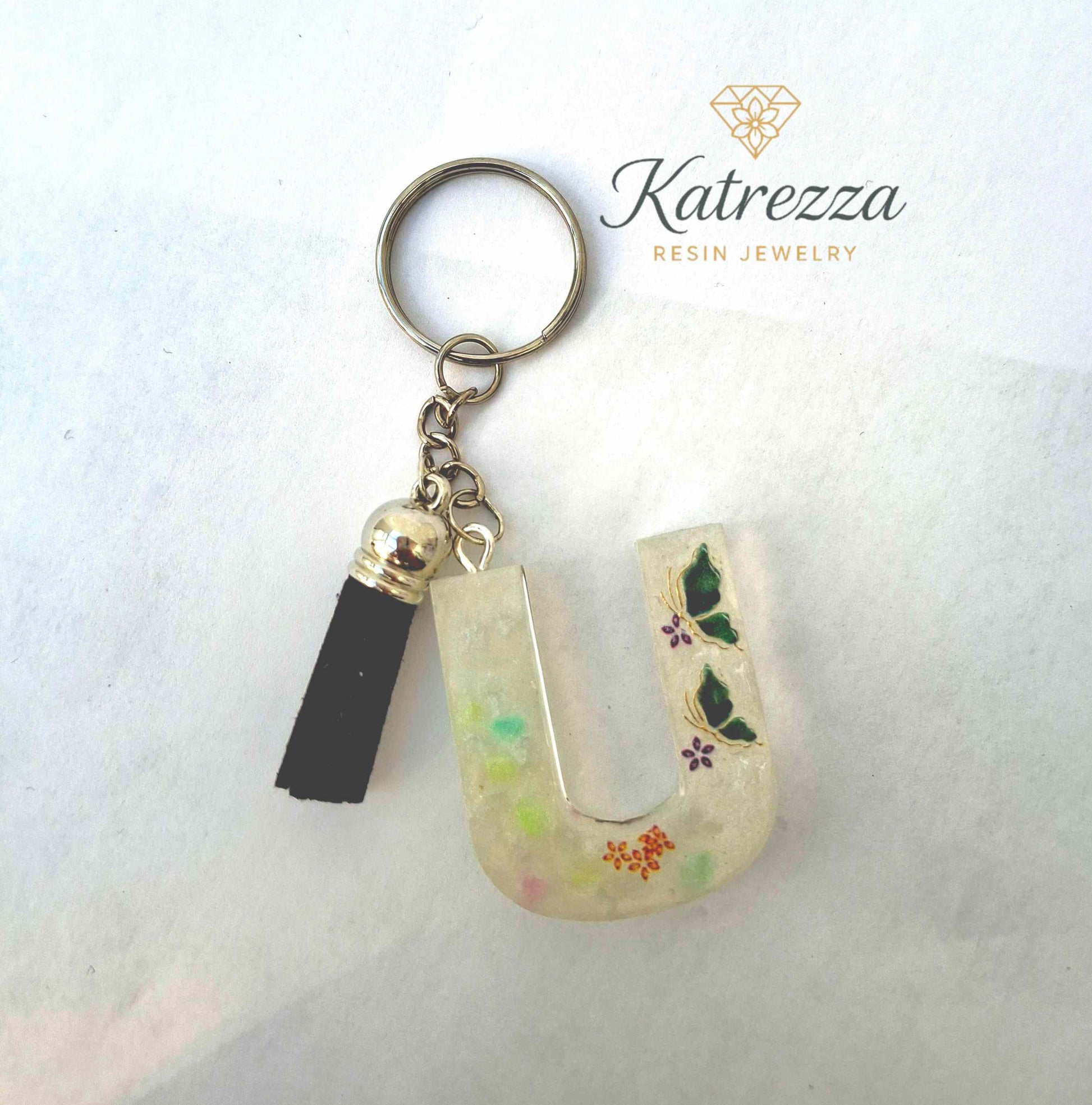 Close-up of resin letter U keychain showing butterflies and floral desi
