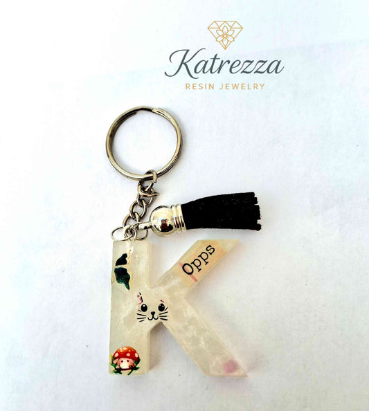 Resin letter K keychain with butterfly, cat face, mushroom stickers and tassel charm.