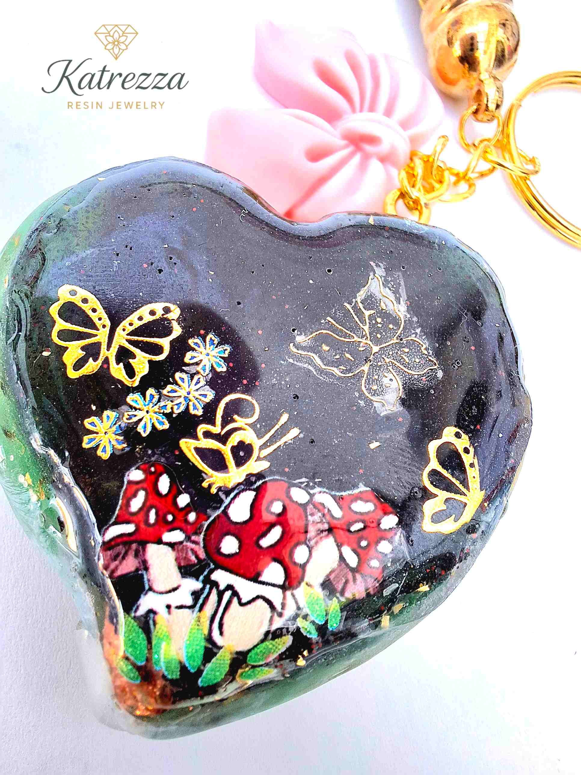 "Close-up of resin heart charm with golden butterflies and mushroom design – Katrezza Jewelry Imperfection Collection"
