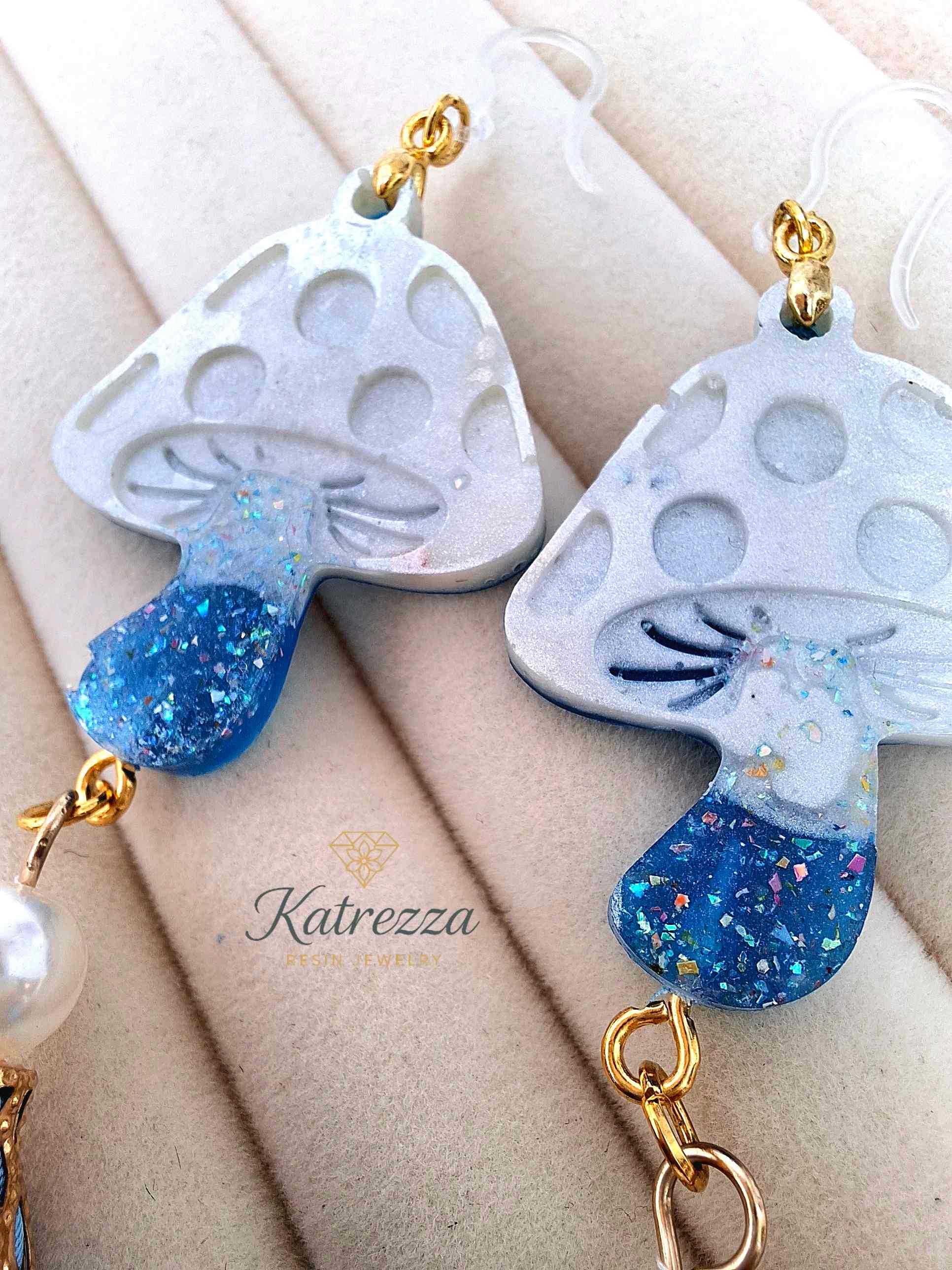 "Pair of double-sided resin mushroom earrings with pearl beads and blue flower charms displayed on black card – Katrezza Jewelry"