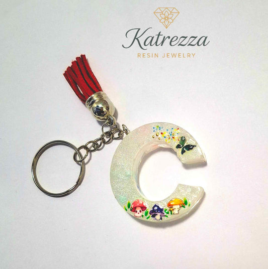 Resin C keychain with red tassel, mushroom stickers, and butterfly decoration.