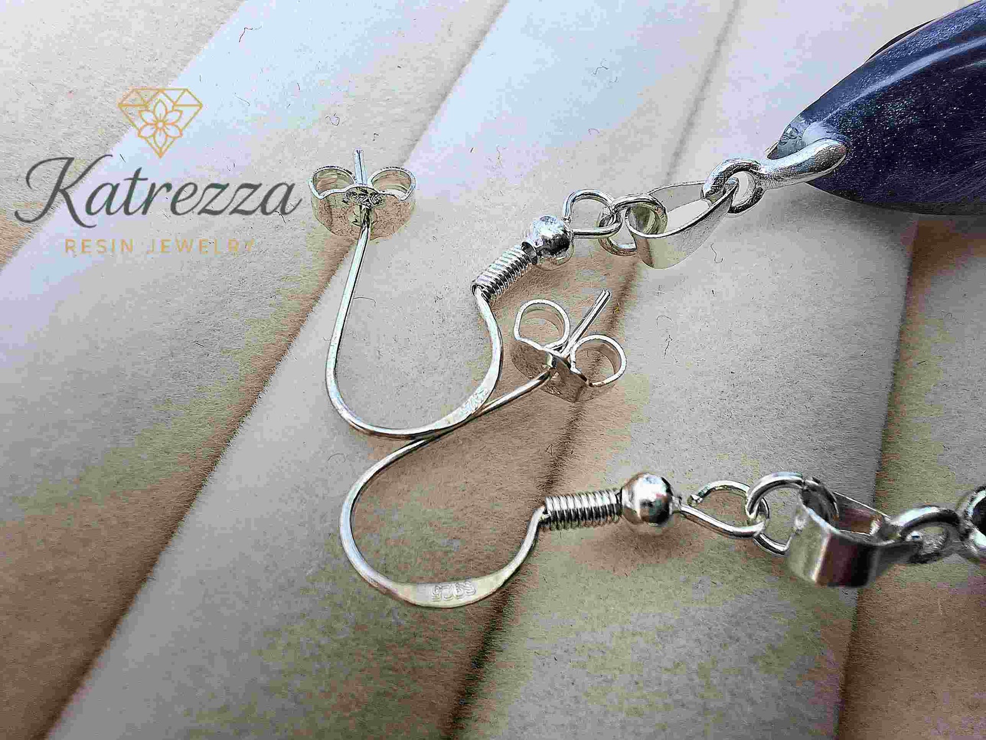 Side view of resin teardrop earrings with dandelion seeds and silver turtle charm.
