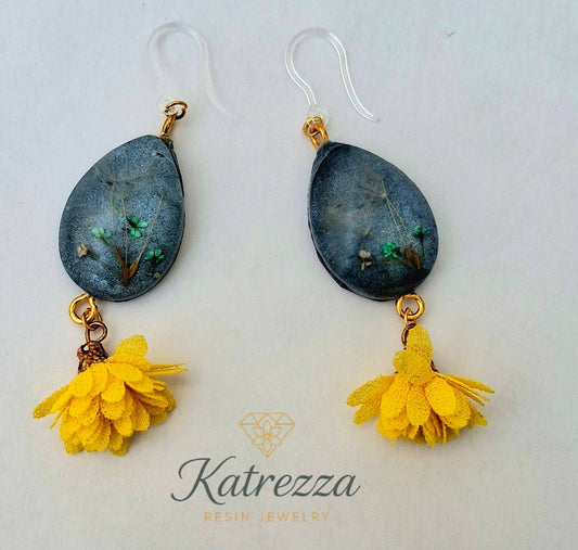 “Teardrop resin earrings with preserved flowers and dandelion seeds, dark resin background, yellow tassels, and silicone hypoallergenic ear hooks – 7 cm.”