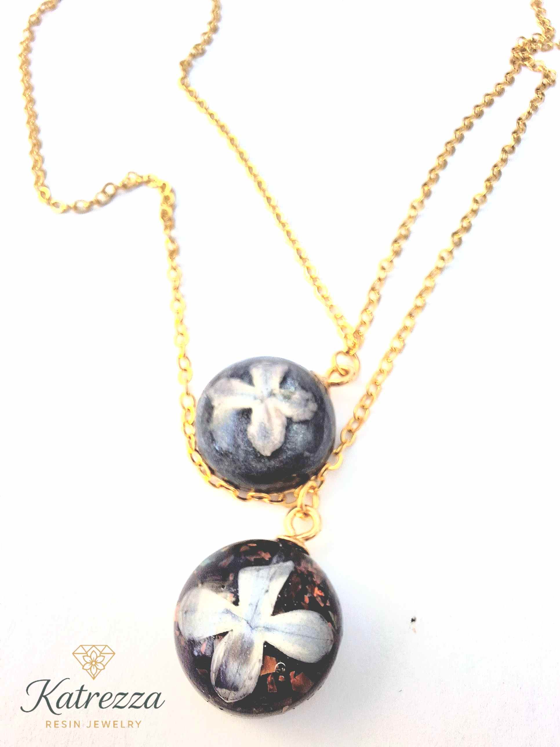 Double layer necklace with two resin pendants featuring real lilac flowers and glitter, on a gold chain – Katrezza artisan jewelry.