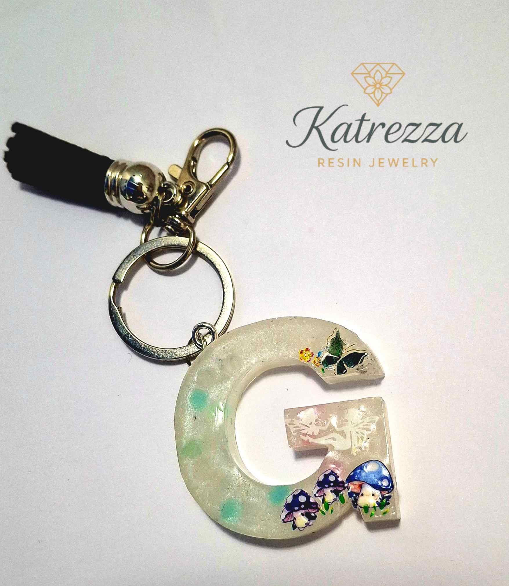 Resin letter G keychain with mushroom and butterfly stickers, black tassel.