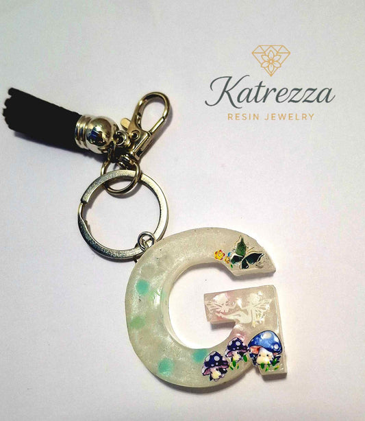 Resin letter G keychain with mushroom and butterfly stickers, black tassel.