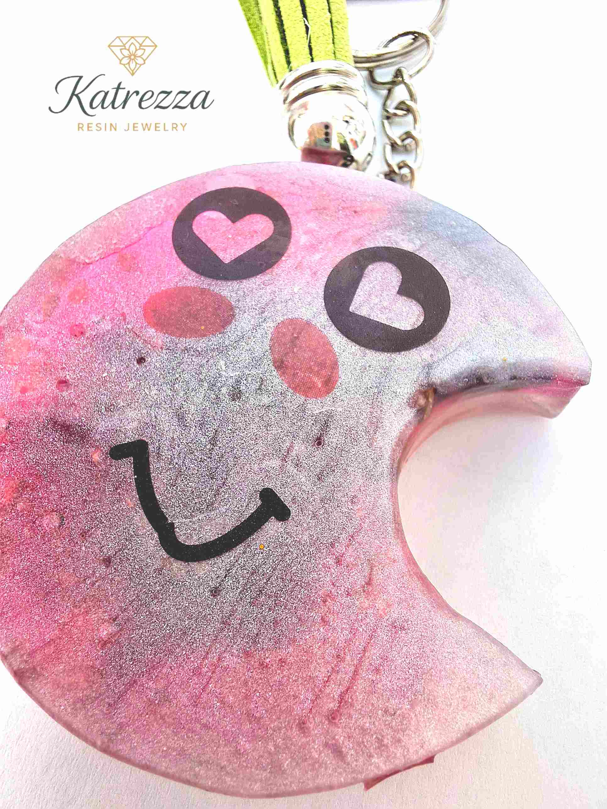 Smiley face design on pink glitter resin moon keychain.
