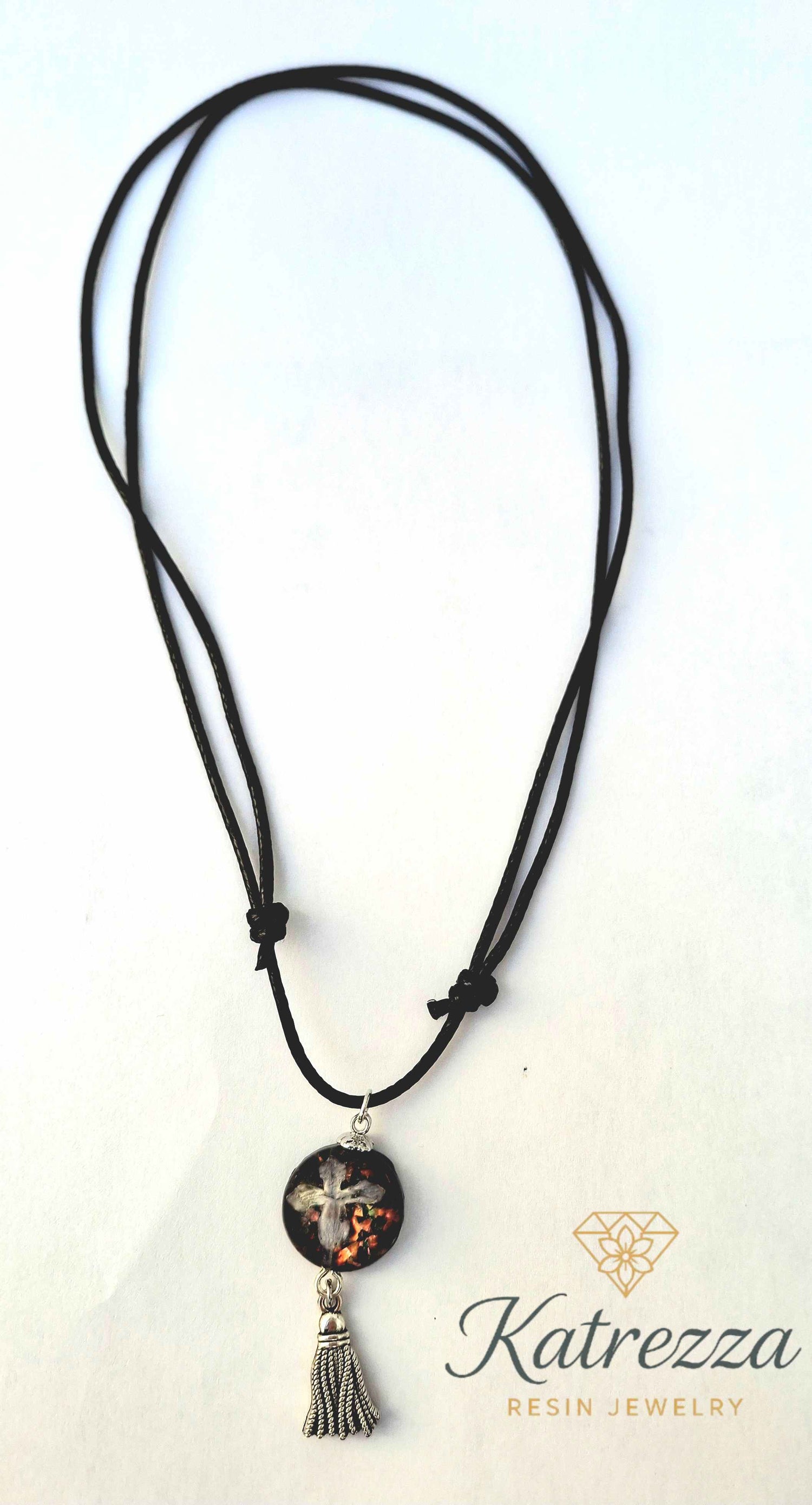 Adjustable black cord necklace featuring real lilac flower in resin pendant with glitter and silver tassel charm – Katrezza artisan jewelry.