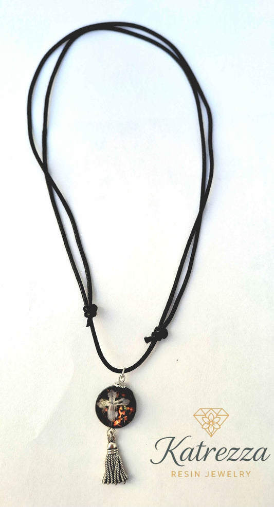 Adjustable black cord necklace featuring real lilac flower in resin pendant with glitter and silver tassel charm – Katrezza artisan jewelry.