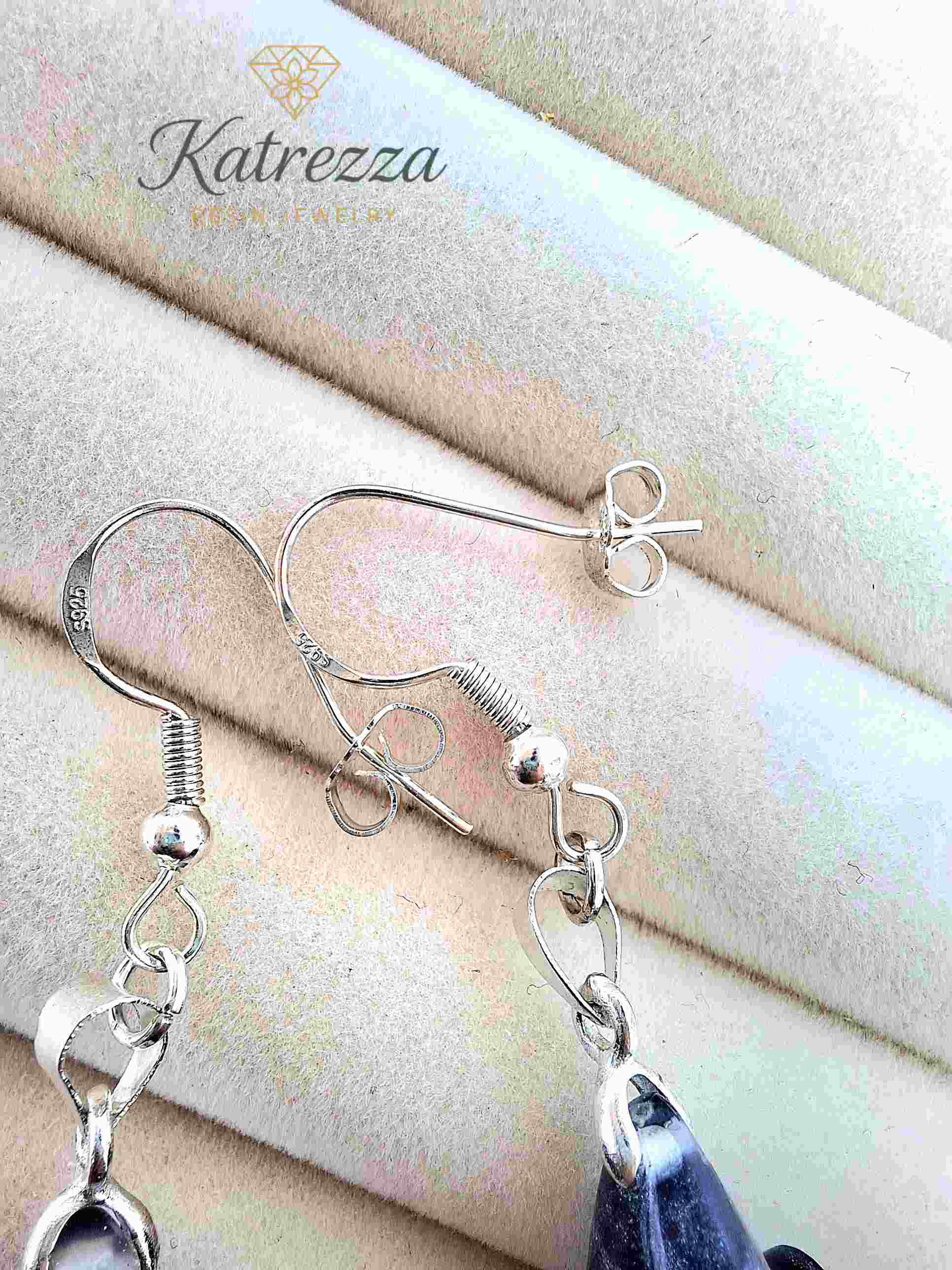 Close-up of glittery resin earrings with dandelion bouquet and sterling silver hooks.
