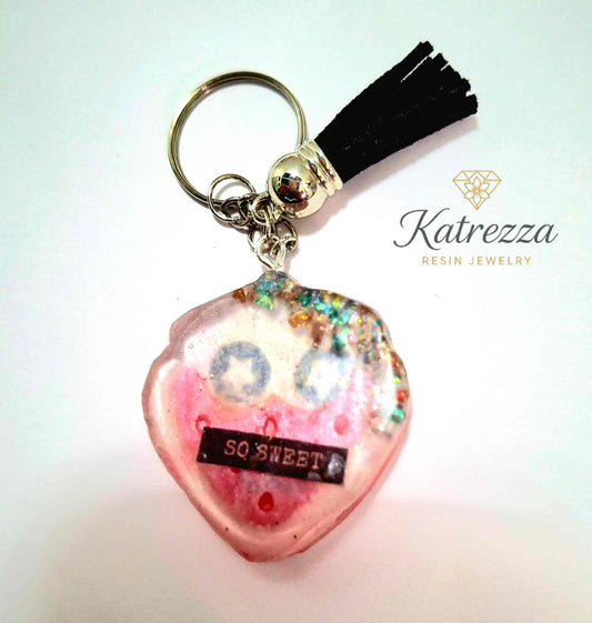 Handmade resin keychain with glitter, pink smiley face, and “SO SWEET” label from The Imperfects Collection by Katrezza Resin Jewelry.
