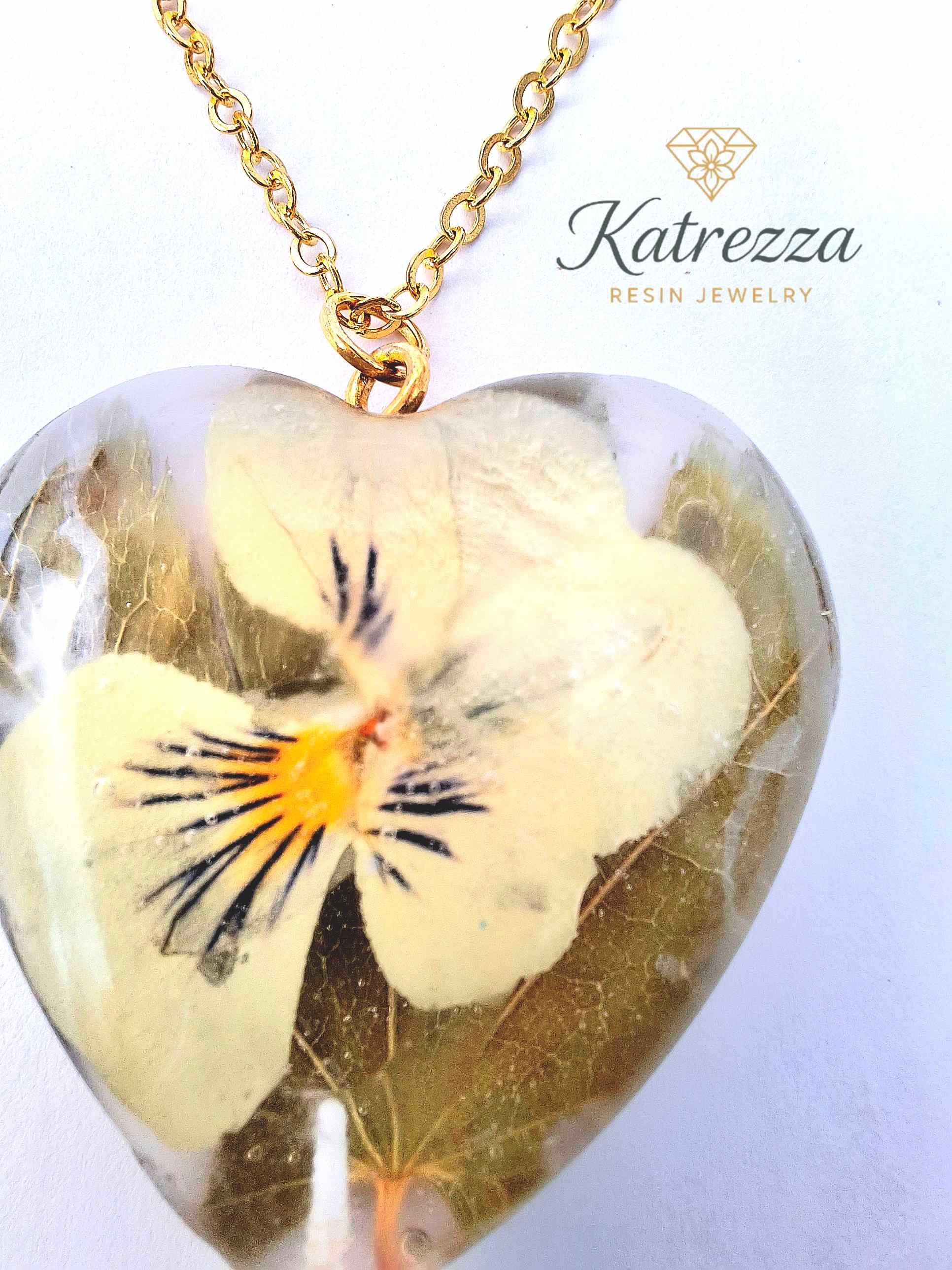 “Heart resin pendant with preserved real pansy flower inside, gold chain detail – Katrezza handmade jewelry.”