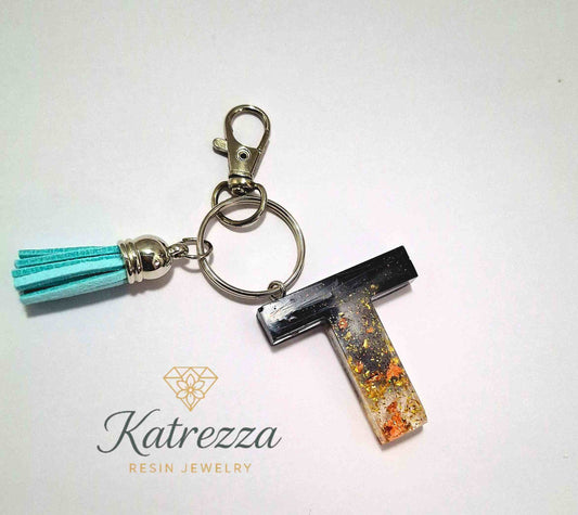 Handmade resin letter T keychain with black resin top, gold flakes, and turquoise tassel by Katrezza Resin Jewelry.