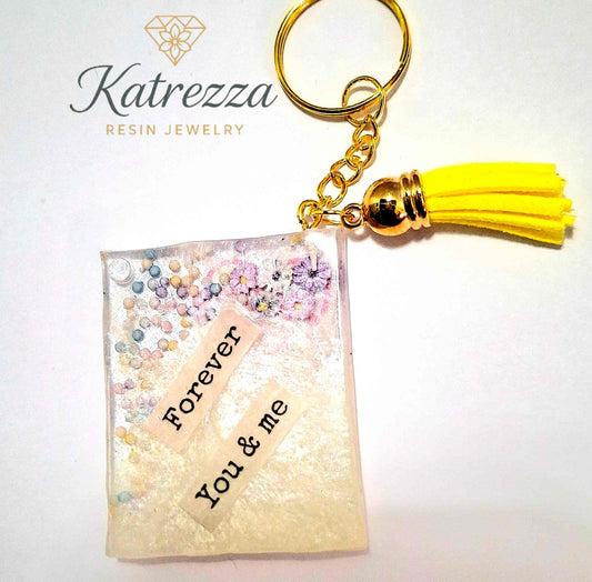 Back side of resin keychain with “Forever You & Me” text and tiny pressed flowers.
