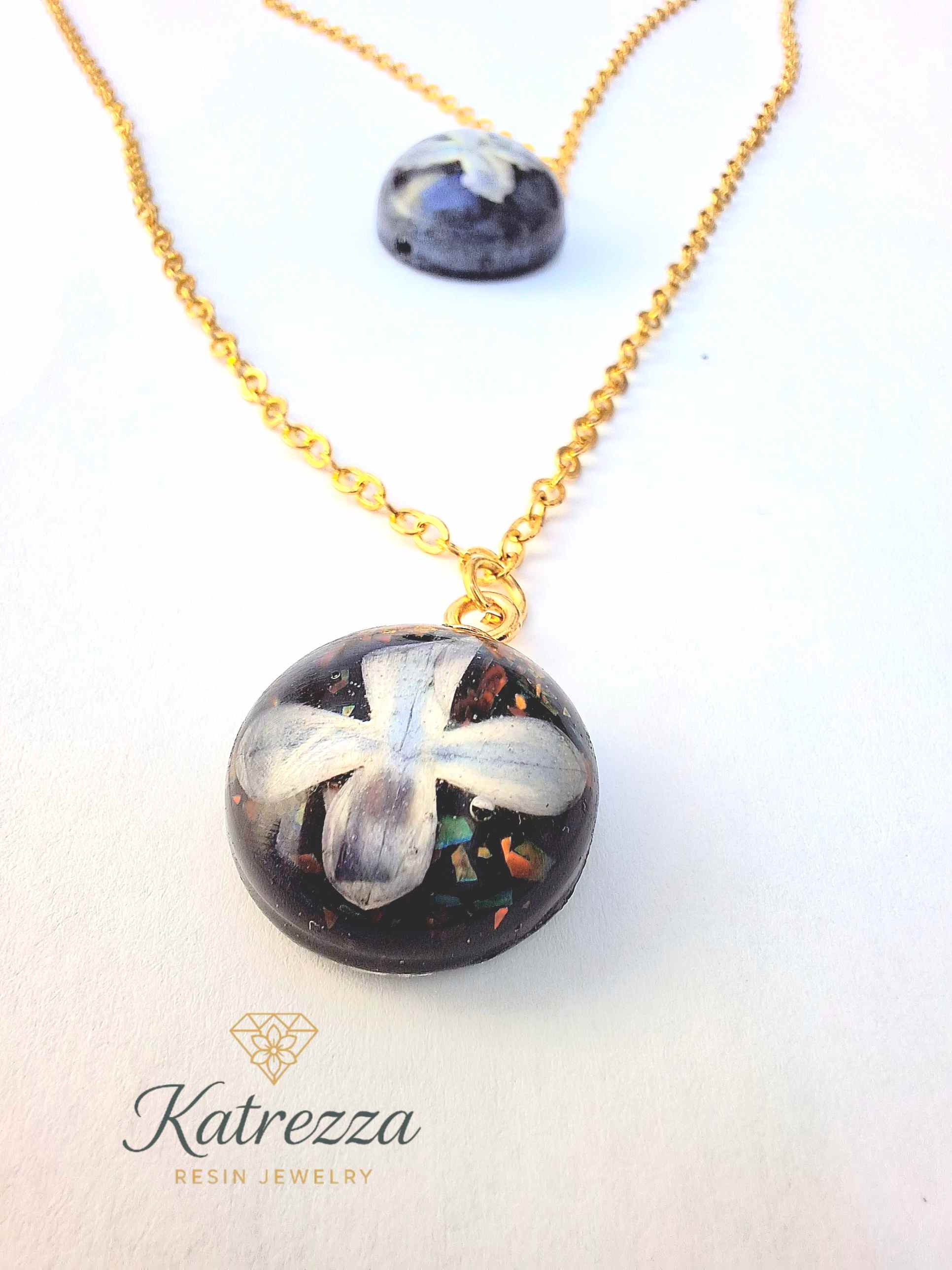 Handmade layered resin necklace with two lilac flower pendants preserved in resin, on gold chain – Katrezza resin jewelry.
