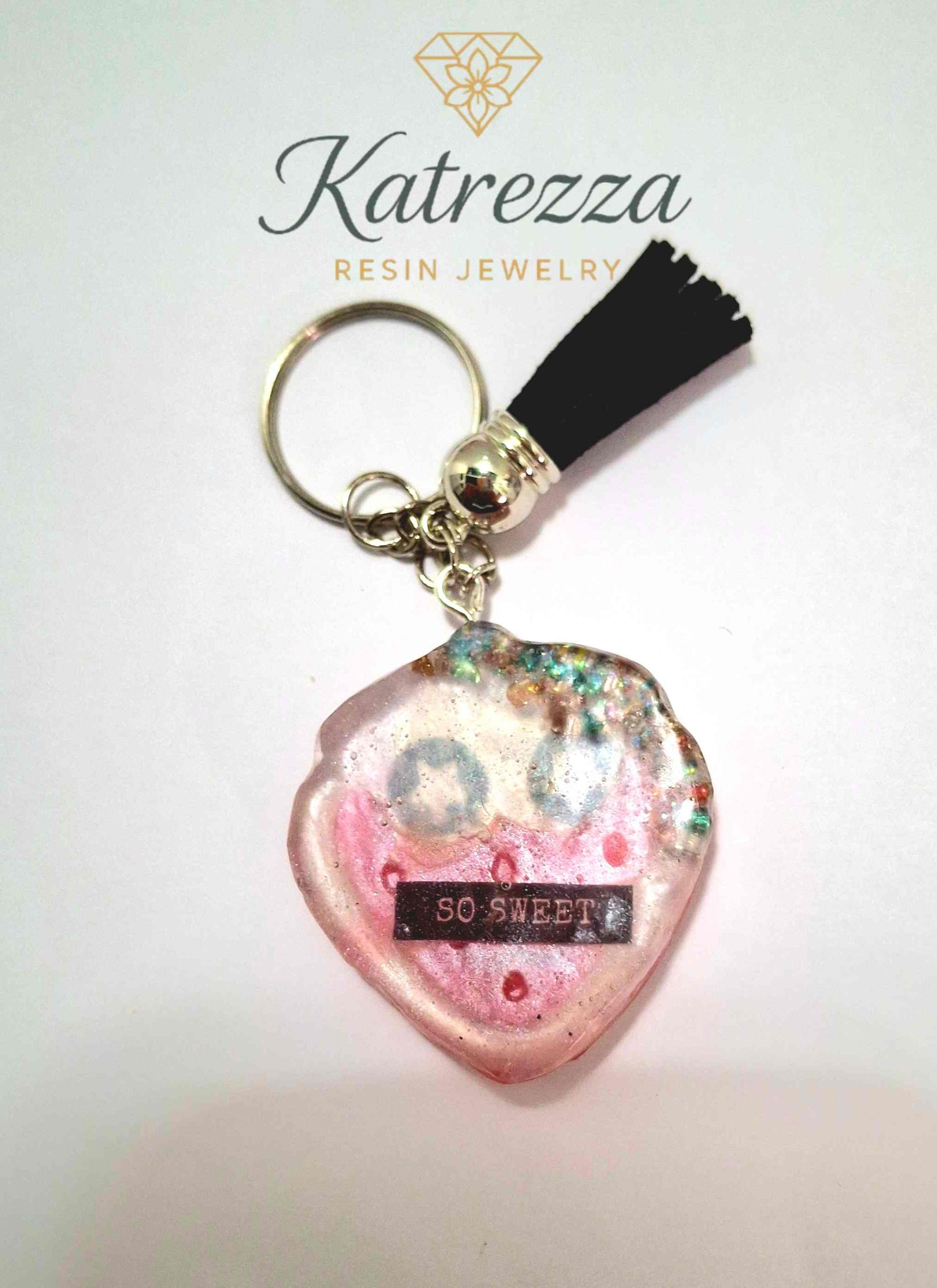 Cute heart-shaped resin keychain with smiling pink face and text “SO SWEET,” part of The Imperfects Collection at Katrezza.